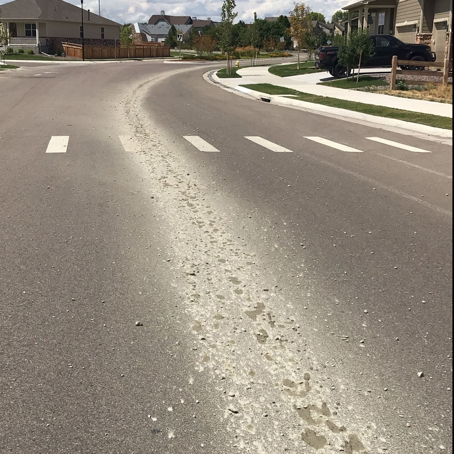 Concrete waste down the length of a road from a concrete truck.