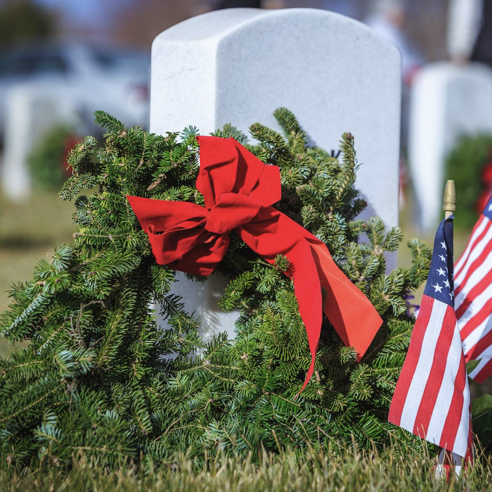 Image of a wreath and a U.S. flag beside a tombstone