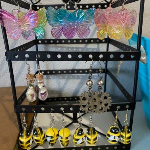 Rack of earrings with butterflys, gears, bumblebees, and shell jars.