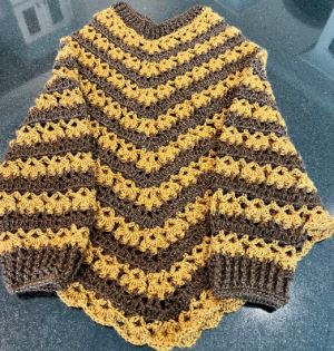 Crocheted poncho with sleeves. Striped yellow and brown. 