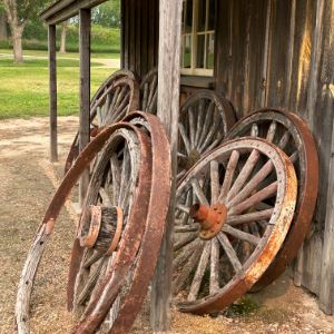 Photograph of antique wagon wheels leaning against a barn. 