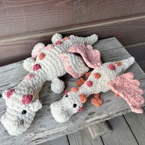 Two pink and white crocheted dragon plushies 