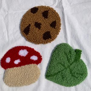 Woven coasters in the shapes of a leaf, a mushroom, and a cookie. 